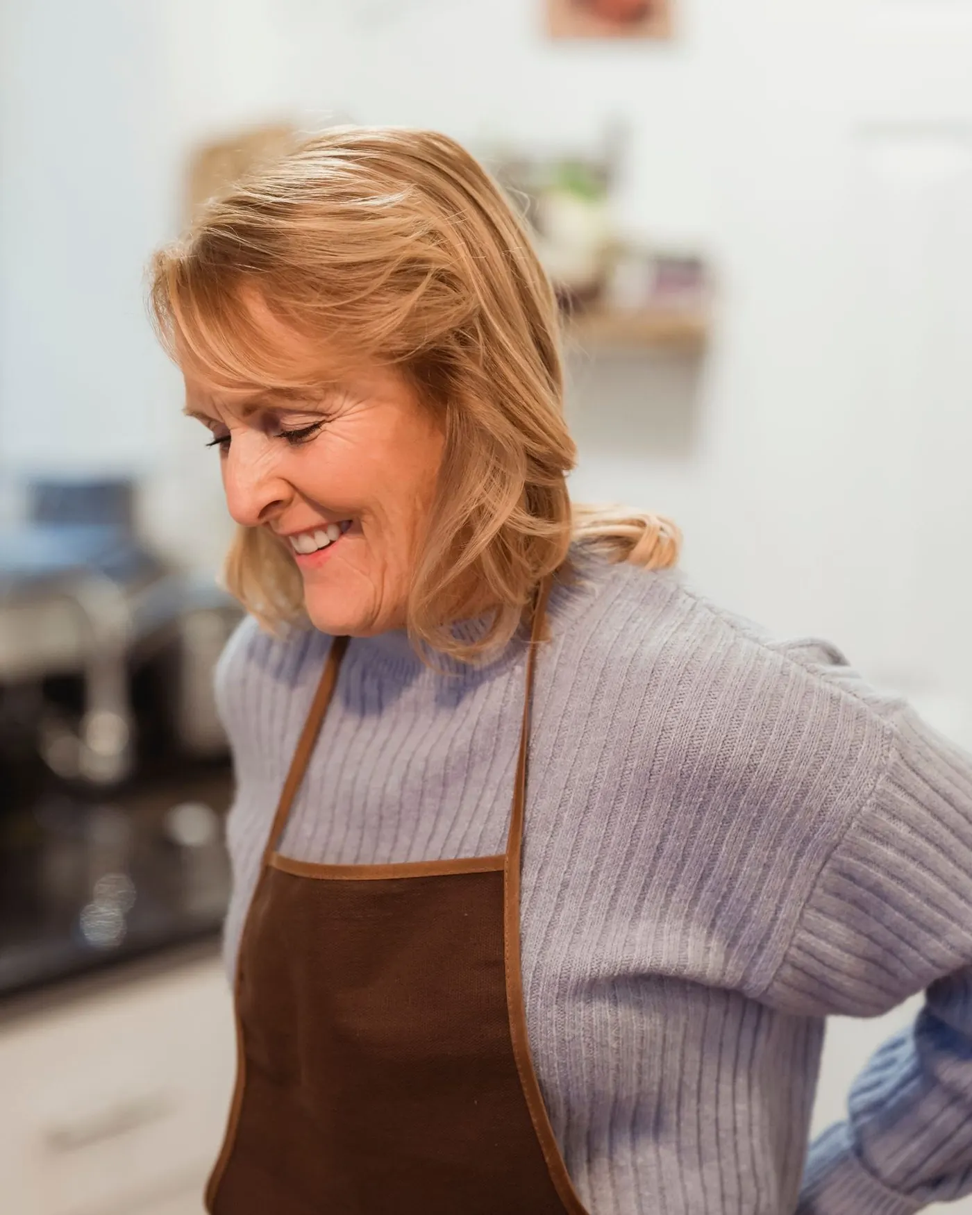 Smiling restaurant owner in an apron in her kitchen (illustration photo)